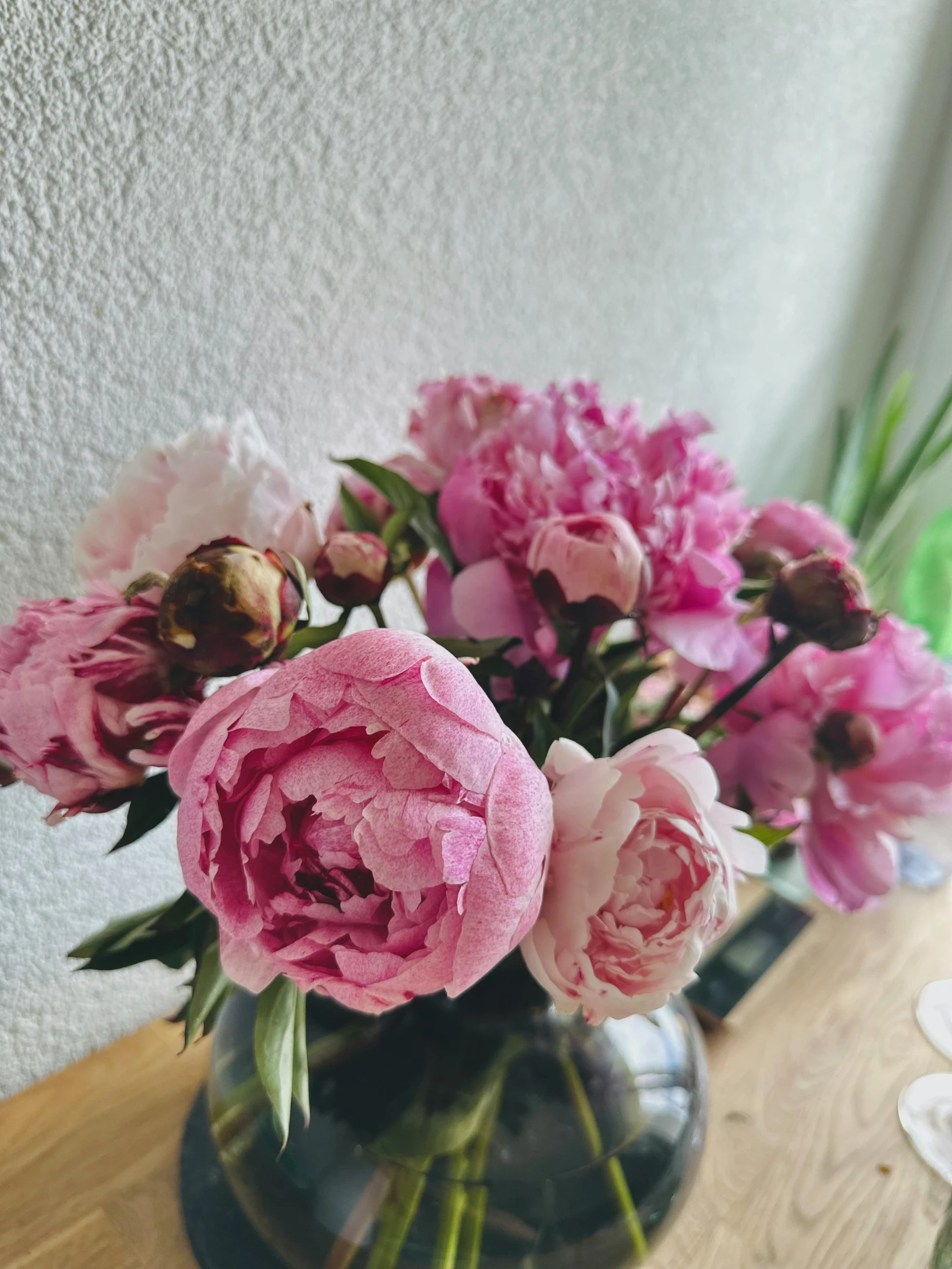 vases of pink flowers sitting on top of a wooden table
