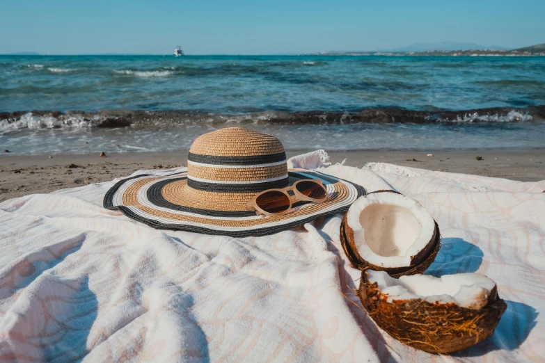 a straw hat and sunglasses lay on a towel at the beach
