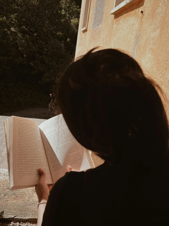 a person sitting next to a building while reading a book