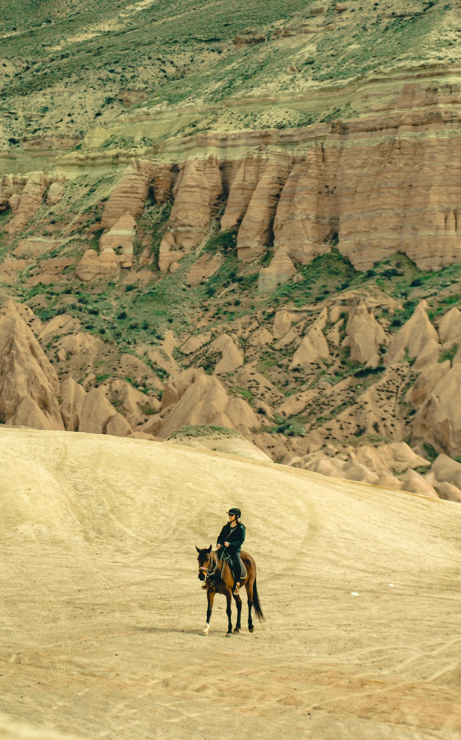 a man rides a horse up the mountain side