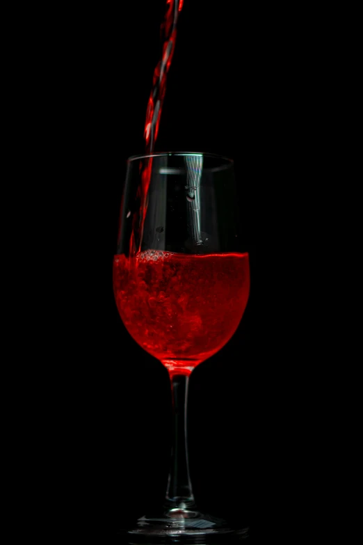 a wine glass filled with red wine and splashing liquid