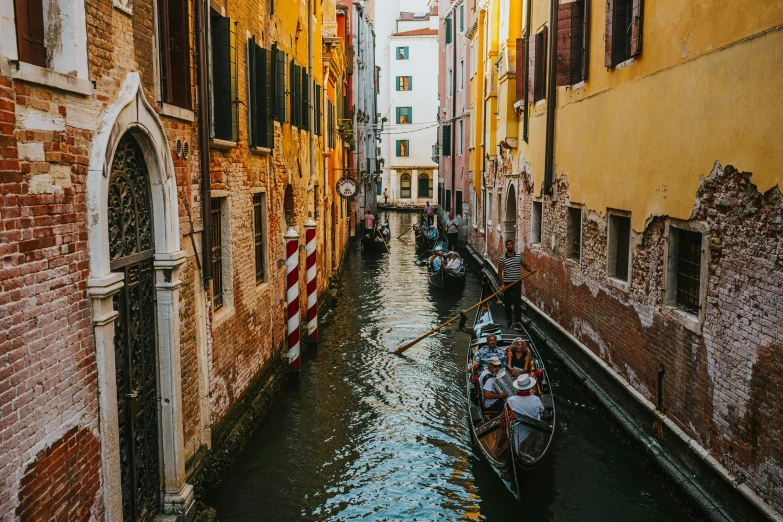 boats are going down a narrow waterway in venice