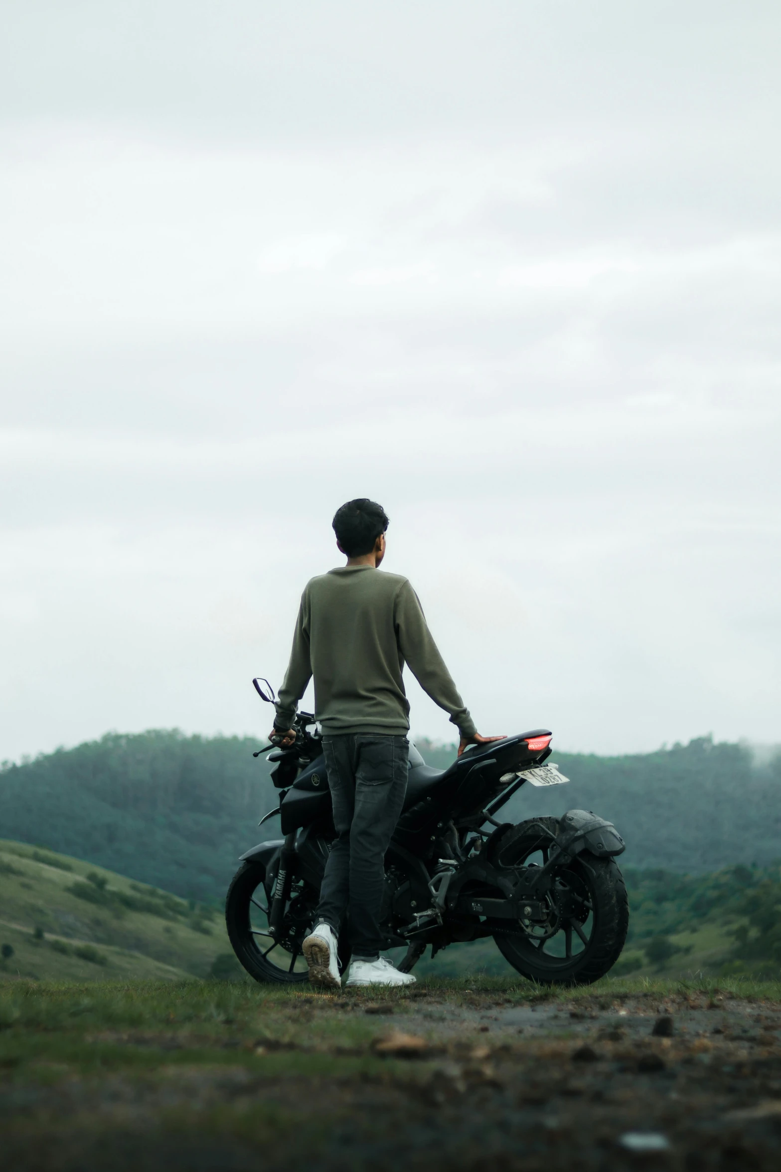 the man is standing next to his motorcycle on the grass