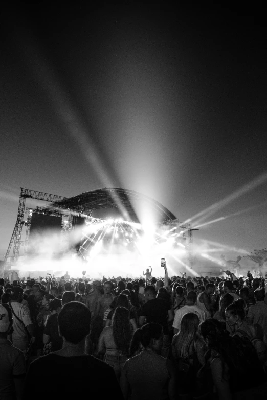 a large crowd of people are sitting on the floor at an outdoor concert