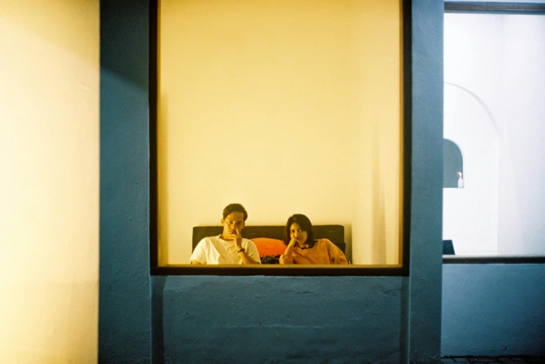 two people sitting on a couch with one holding a phone