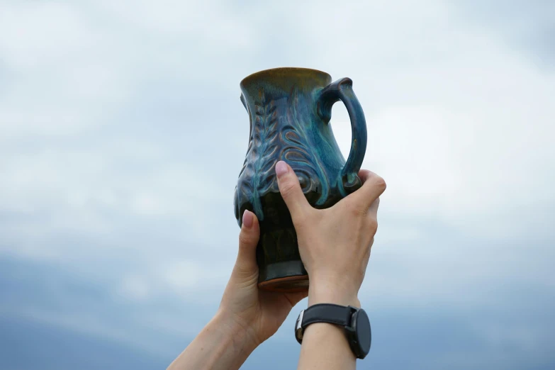 a person holding up a tall blue coffee cup