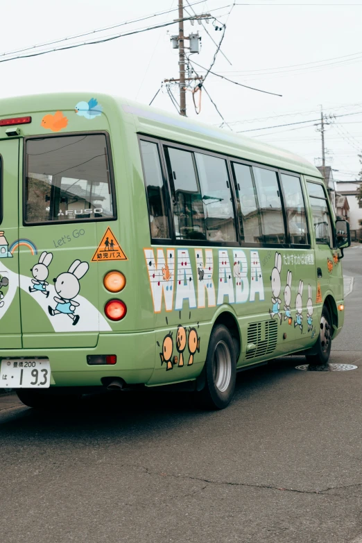 a green bus with pictures painted on it in a parking lot