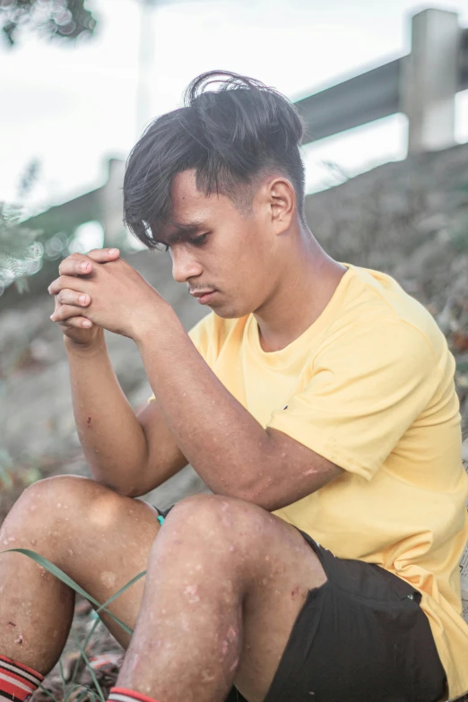 a boy sitting on the ground looking down at his wrist