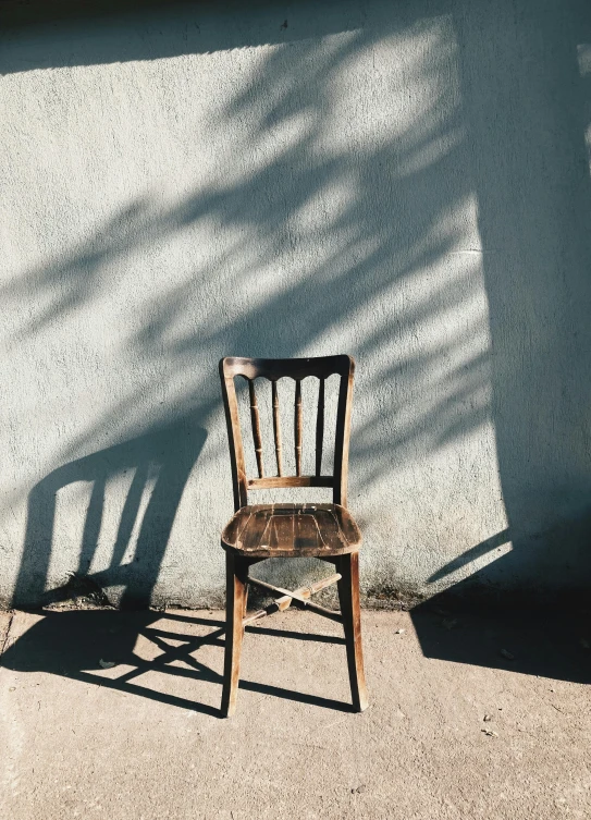 a chair is leaning against a wall in the sun