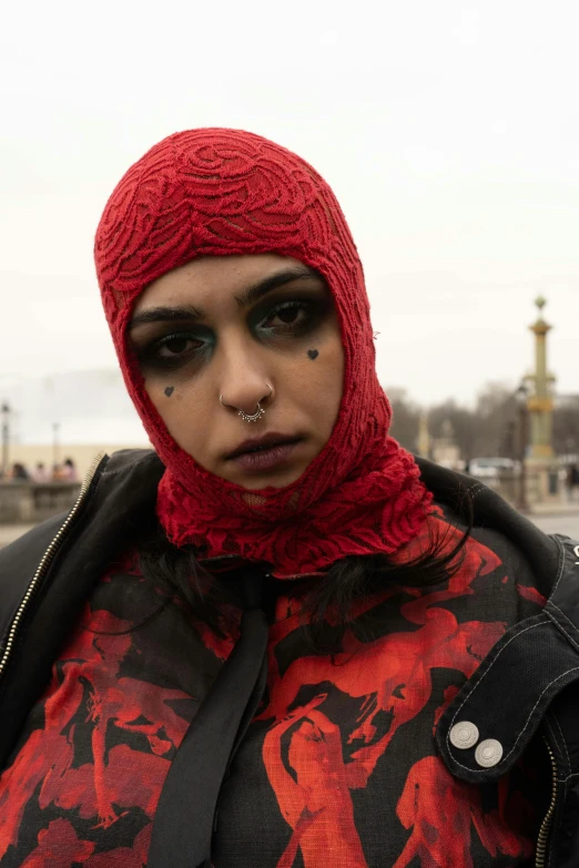 a woman in a red head scarf, with black eye makeup