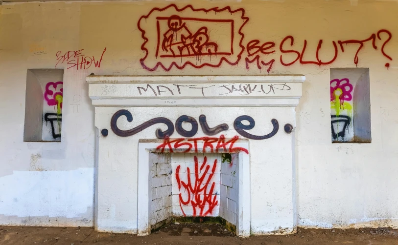 a graffiti - covered fire place and wall next to a parking lot