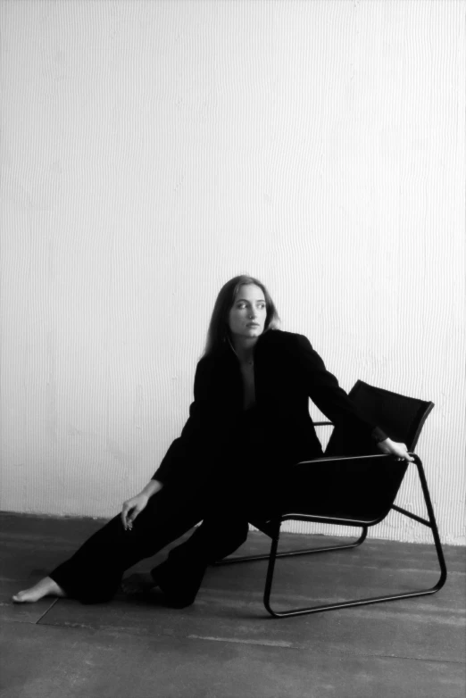 a woman sitting on top of a chair by a wall