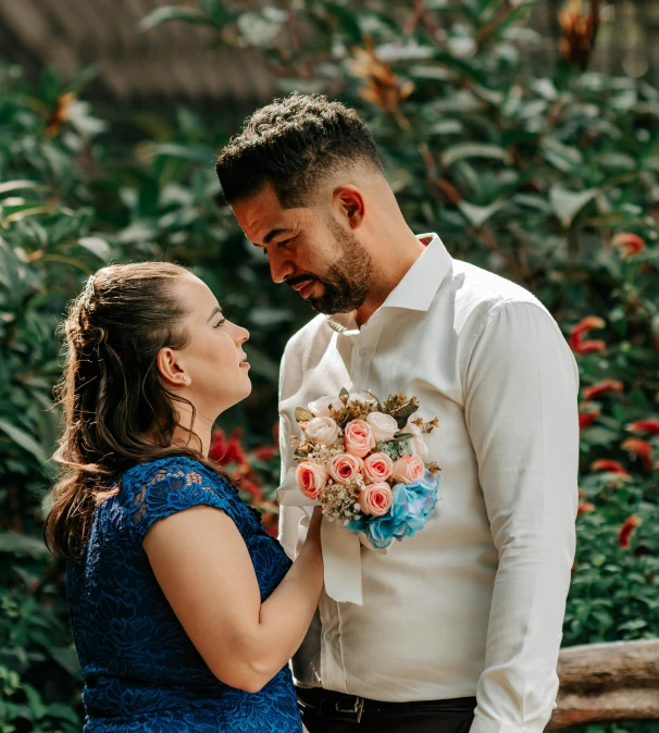 an engaged couple laughing together in the midst of trees and flowers