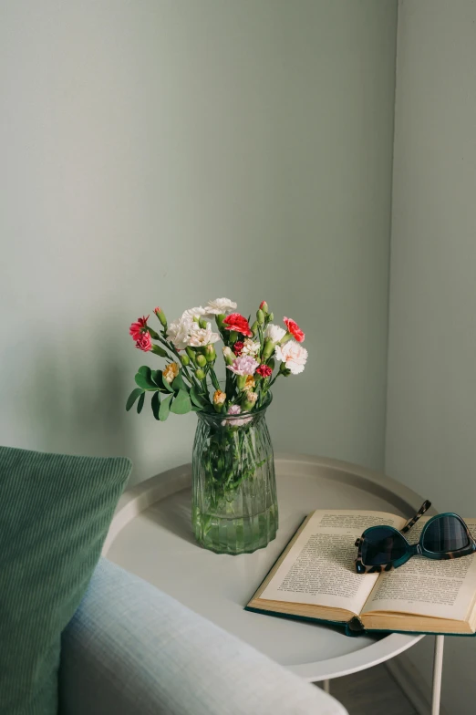 vase with flowers and sunglasses on small table