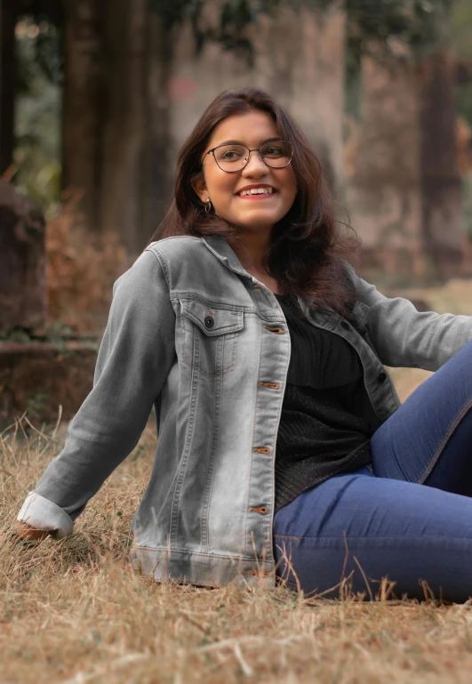 a woman with glasses sitting on the ground