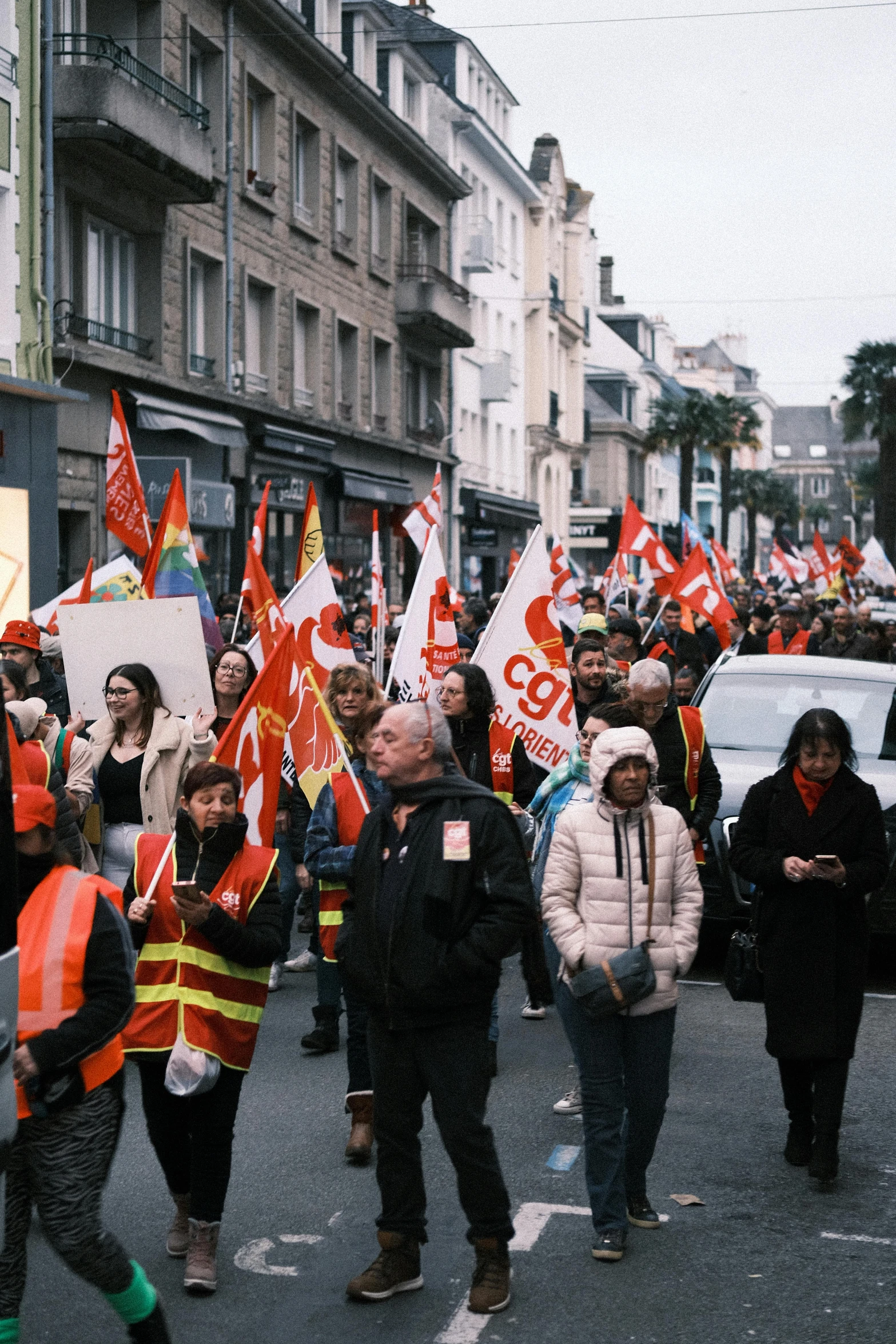 people walking down the street holding flags in front of some cars