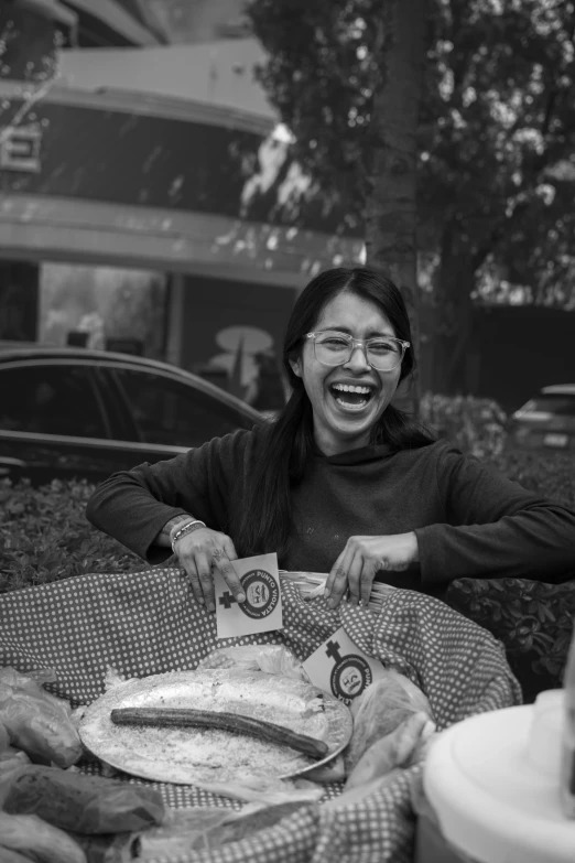 a woman smiles and points to food she is holding