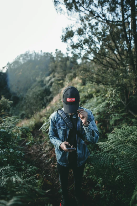 a man walking through the forest with his phone in hand