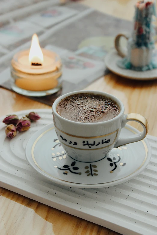 cup on saucer with candle light in background