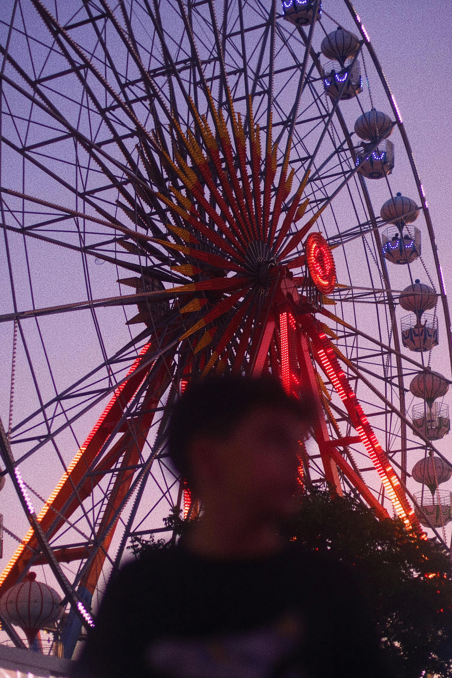 people are walking around in front of a ferris wheel