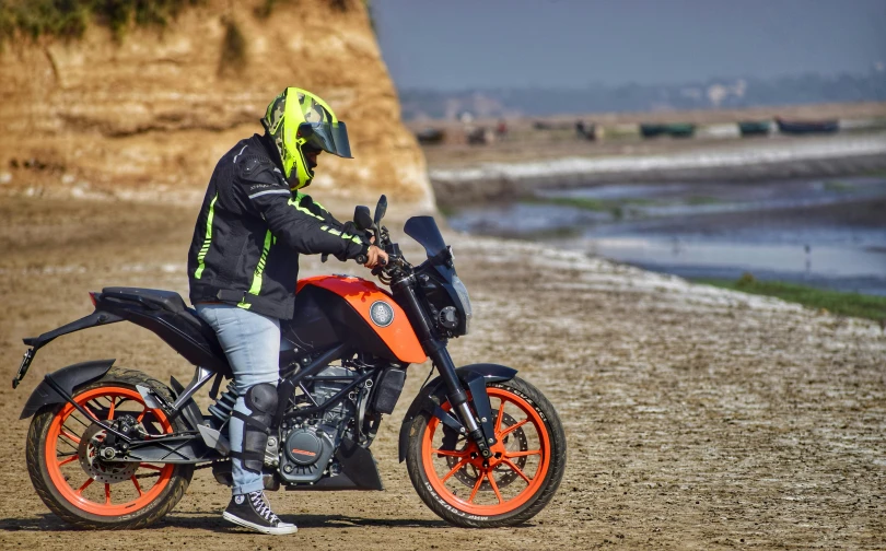 a person in motorcycle gear rides a motorcycle on the beach