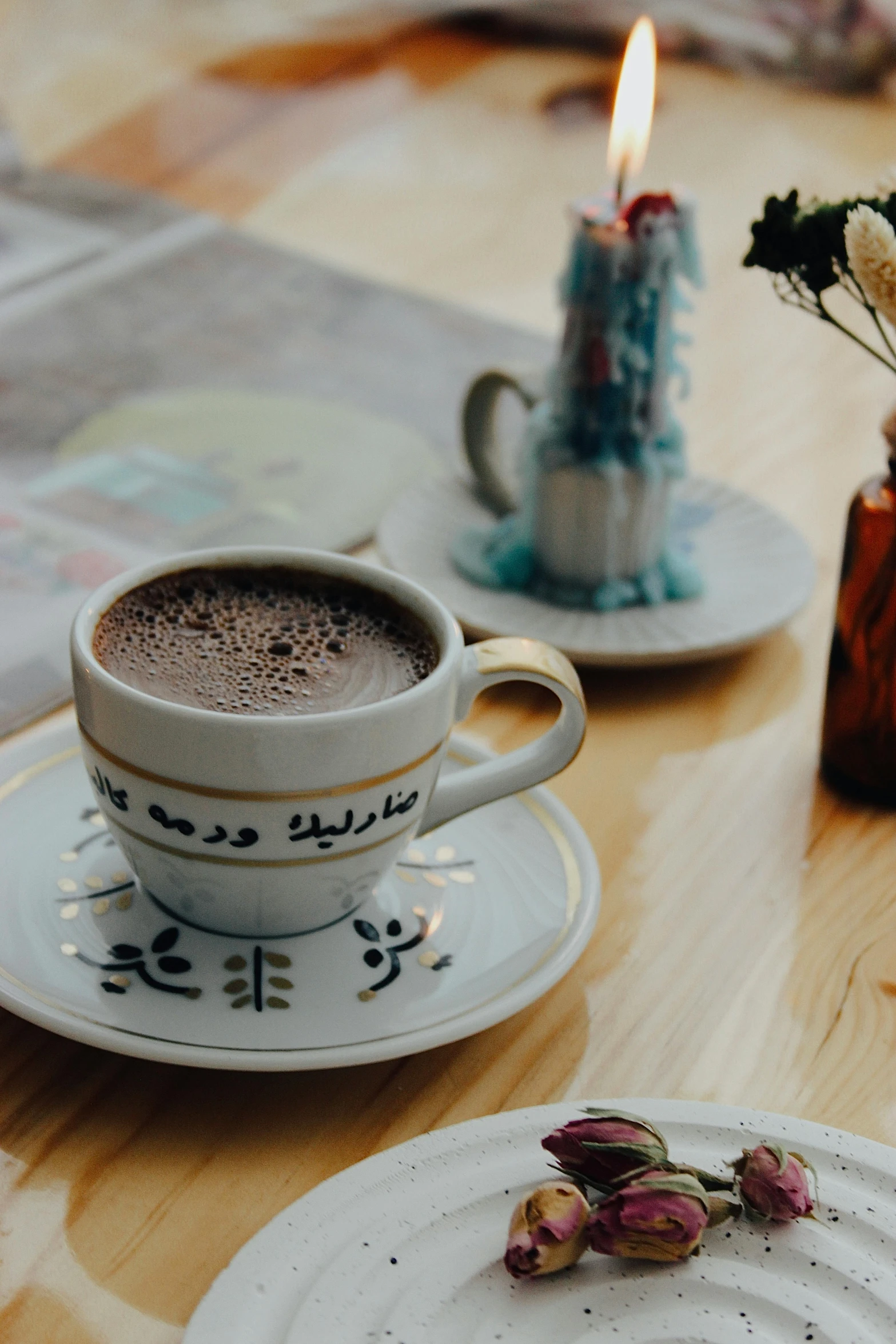 a cup of  chocolate in front of two plates with small flower stems