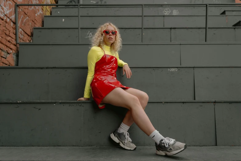 woman in a red vinyl skirt sitting on steps wearing high tops