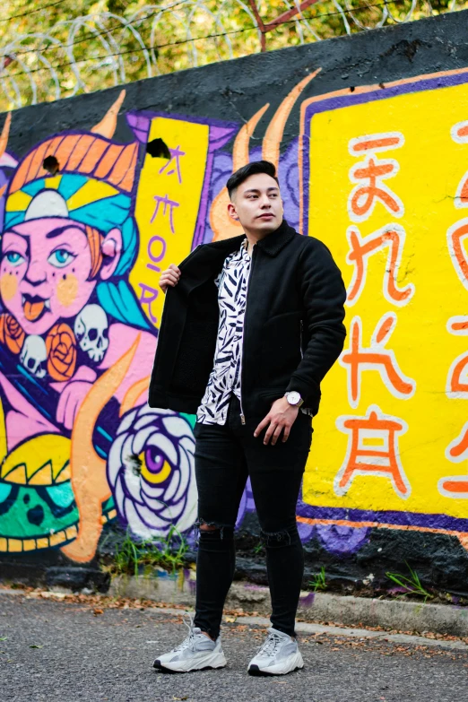 the man is posing in front of colorful mural