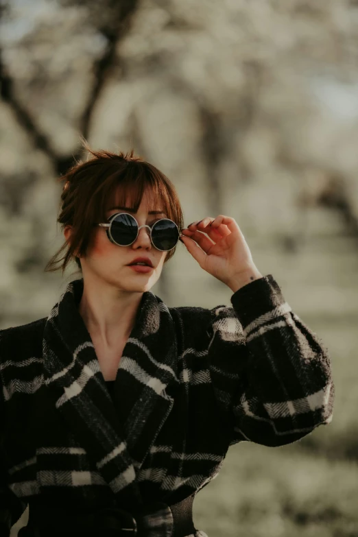 a woman looking through her sunglasses in a jacket