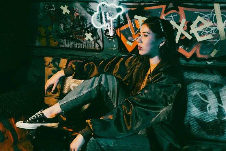 a woman sitting on a bench near a wall covered in graffiti