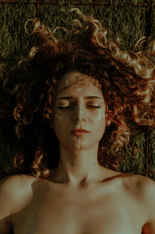 a woman laying on the grass looking directly in the camera