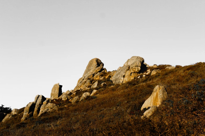 some rocks and grass a hill and sky