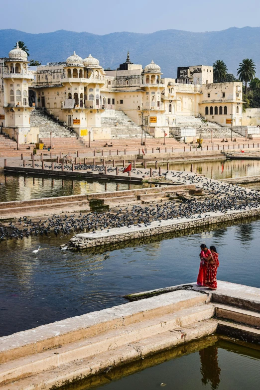 some people standing by some water and buildings