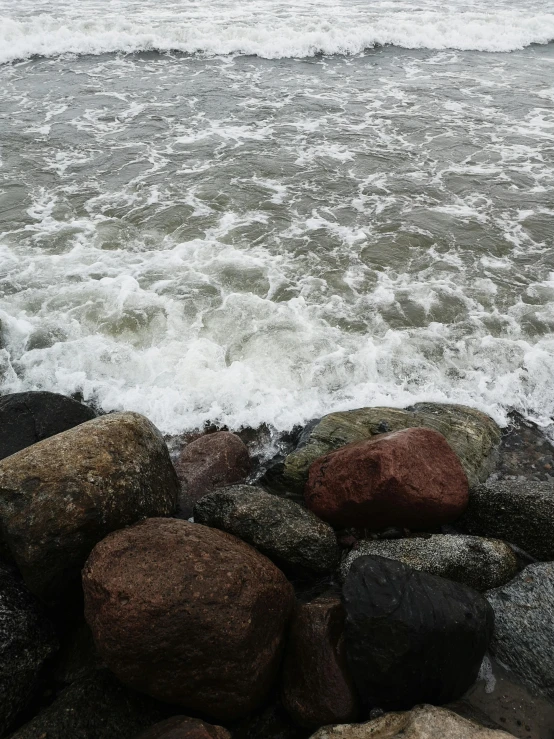 a beach with several rocks and a surfboard sitting on it