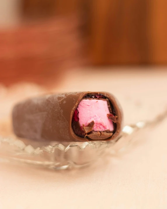 a piece of chocolate and pink candy on a spoon