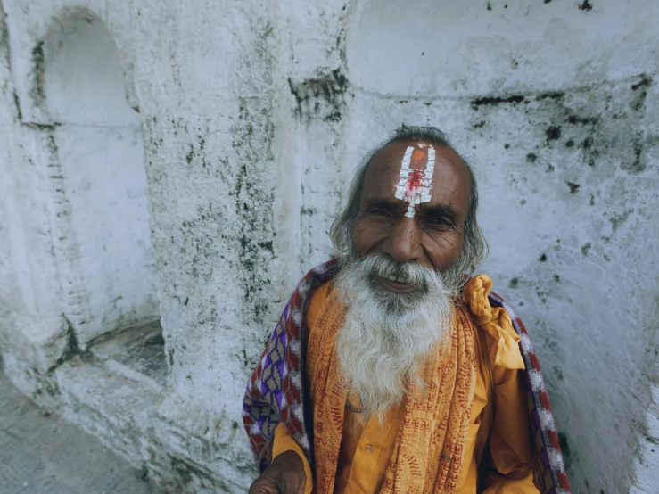 a man with long white hair and beard wearing a yellow outfit standing in front of white walls