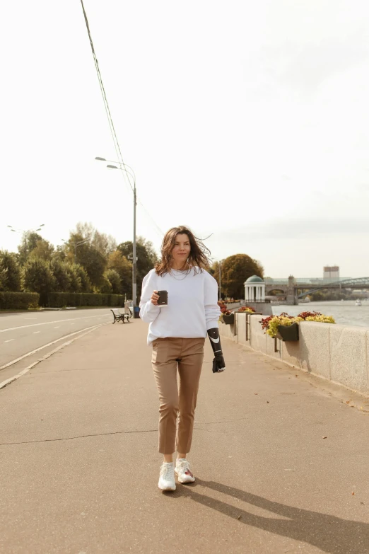 a woman wearing a sweater and leg warmers is walking along a street