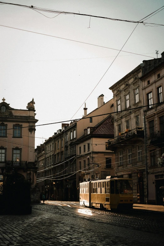 an old tram runs past buildings in the evening