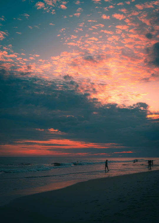 some people at the beach with sky in background