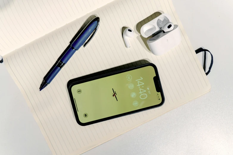 a white desk topped with a blue pen and cellphone