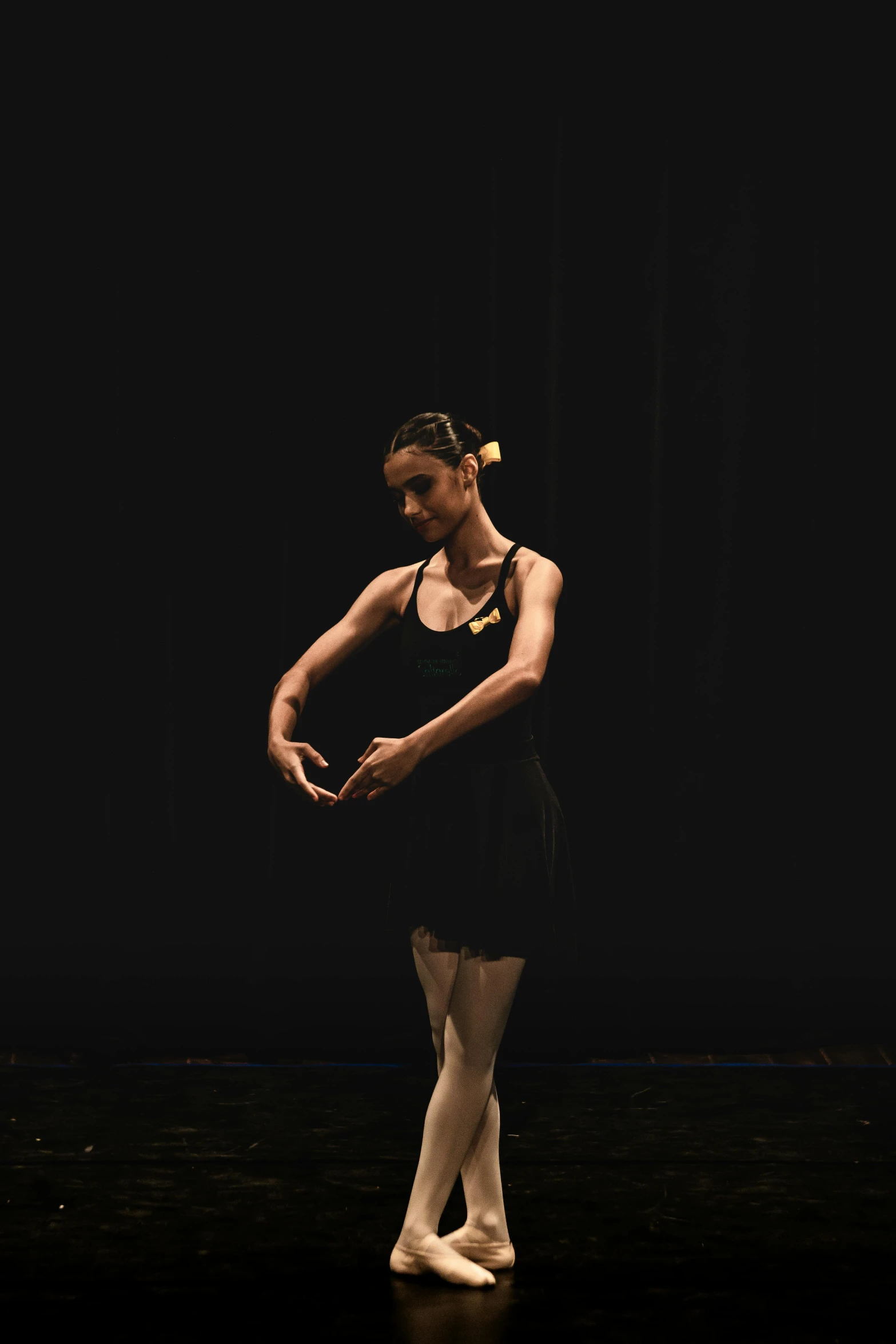 woman in black dress doing ballet moves on dark stage