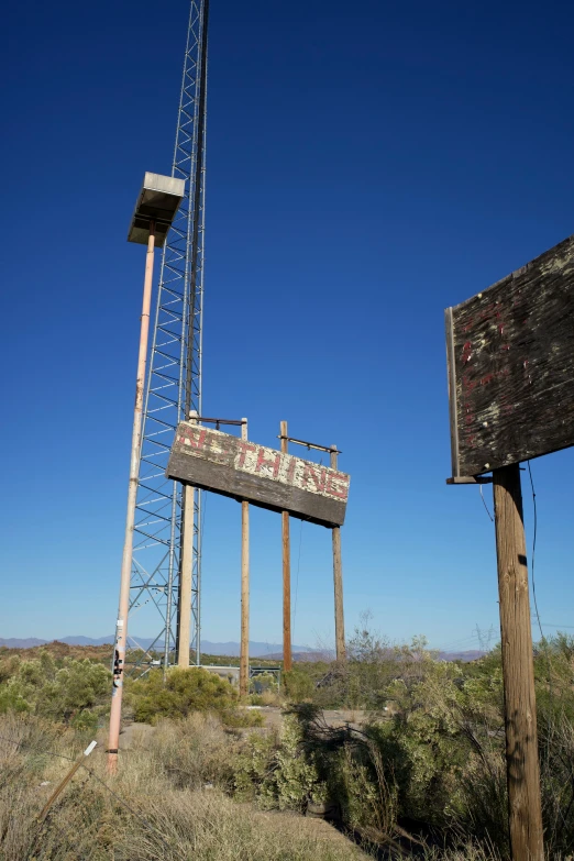 an old rusted out sign sitting next to a tall tower