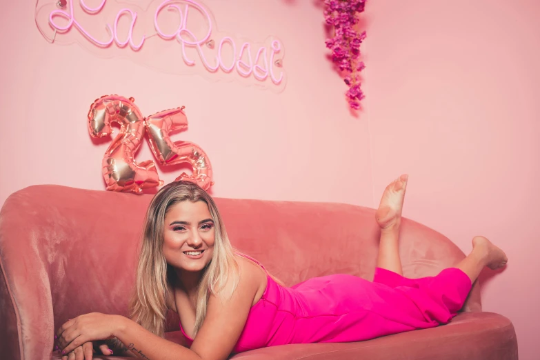 a woman wearing a pink dress laying on a couch