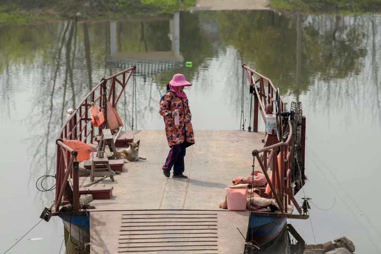 a girl in a pink hat stands on the pier