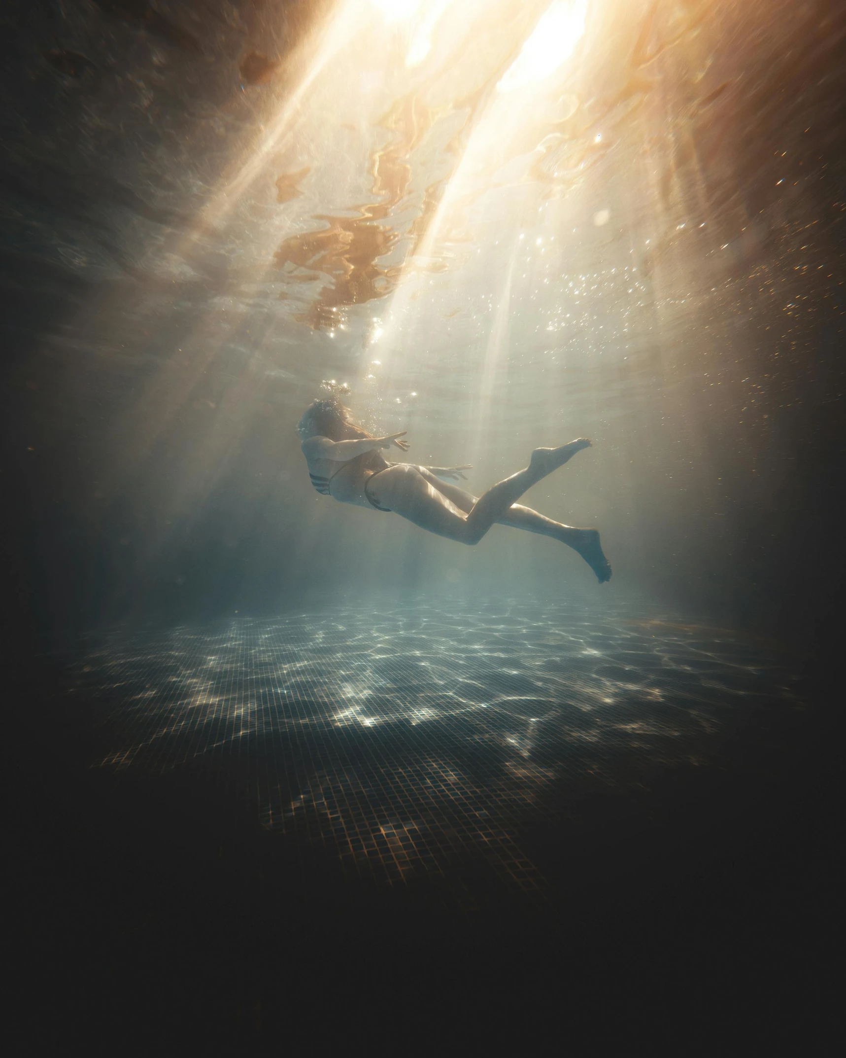 a person swims under water on a sunny day