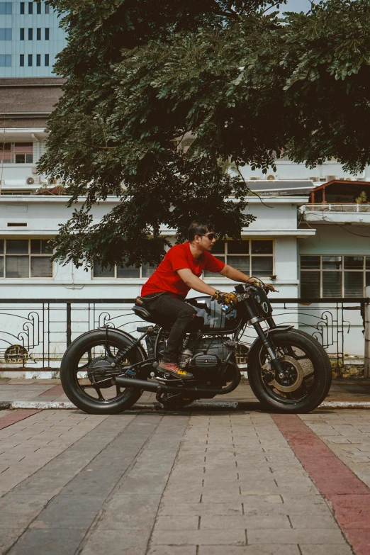 a man on his motorcycle with a tree behind him