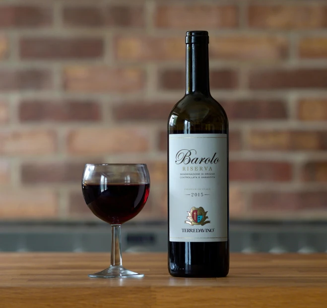 wine bottle next to glass with red wine on table