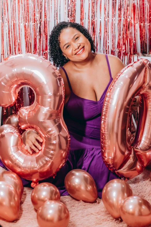 a woman is posing with balloons and smiling at the camera