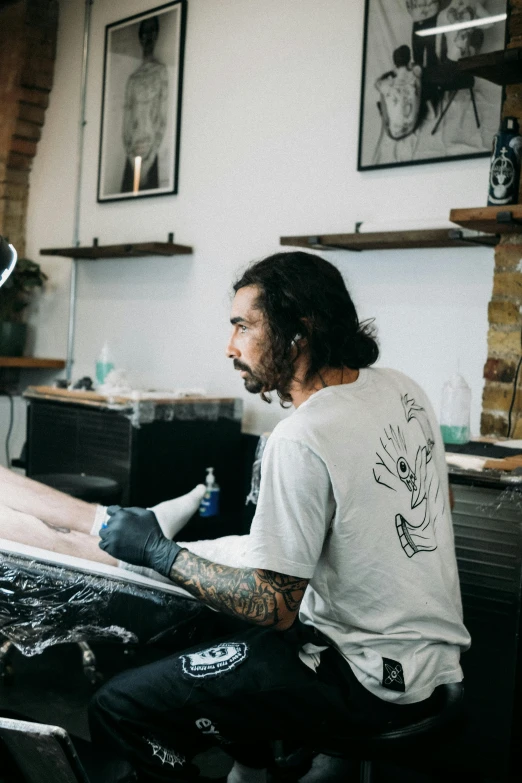 a man with tattoos sitting in front of a printer