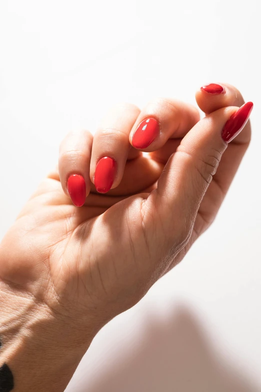 a womans hand with red nails and a celet